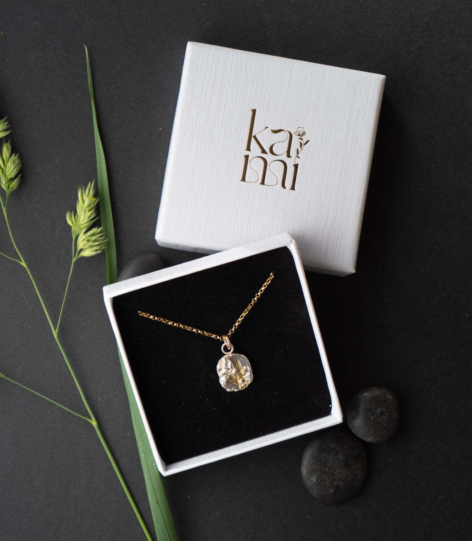 Gold necklace in a box with 'kami' branding on a dark background